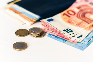 Close up money euro banknotes in blue purse and coins on white background.