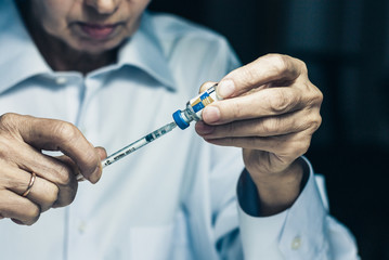 bottle of insulin for diabetes and injection syringe in old woman hands, healthcare concept background.