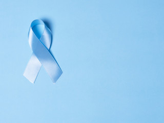Blue satin Ribbon symbol of prostate cancer awareness on a bright blue background. Concept of...