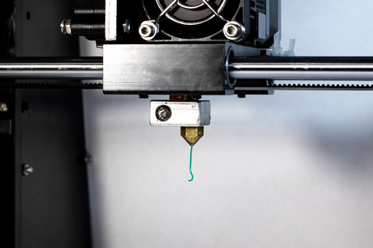 3D printer nozzle and green plastic closeup