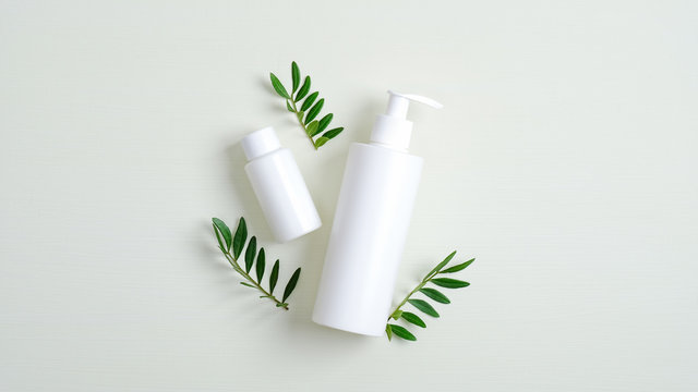Clear cosmetic bottle containers and green leaves. Minimalist cosmetic product mockups. Natural hand care cream and lotion packaging, beauty SPA cosmetic branding concept