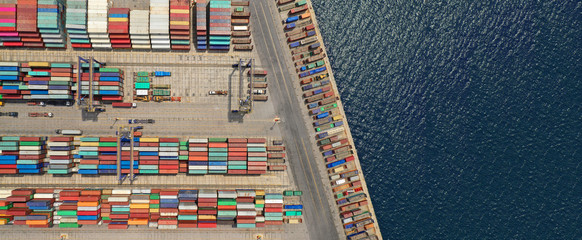 Aerial drone ultra wide top down photo of commercial container terminal with cranes loading...