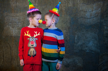 Fototapeta na wymiar Two boys brothers in bright festive attire are holding pumpkins in their hands. Children dictate their message to Santa Claus before Christmas. Pupils sing songs and talk about successful studies