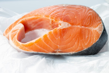 a big piece of raw Atlantic salmon steak on a white creased piece of paper