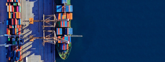 Aerial drone ultra wide top down photo of commercial container terminal with cranes loading...