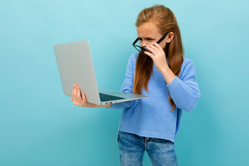 Charming caucasian girl works or studies with laptop isolated on blue background