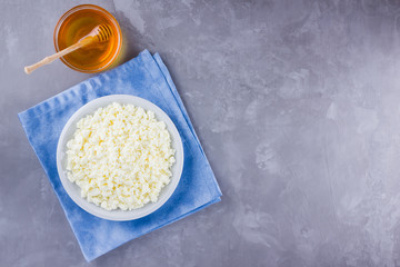 Cottage cheese and honey. Fresh cottage cheese on a gray background. Homemade curd on a blue napkin on cement background. Top view. Copy space