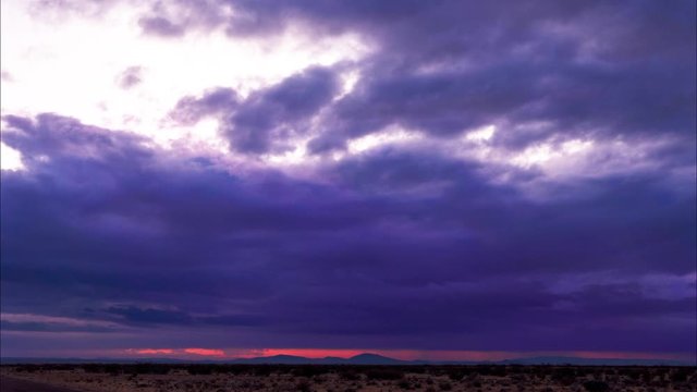 Colorful purple and blue clouds with red sunrise light in Mojave Desert