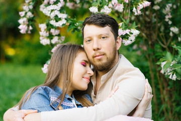 A romantic couple in love embrace in the spring in a blooming lilac garden