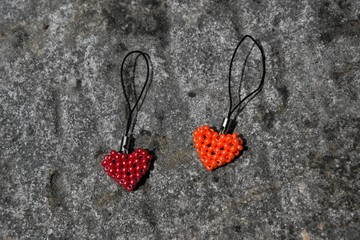 Orange and red heart from the beads on black cord. Pendant lying on stone surface.