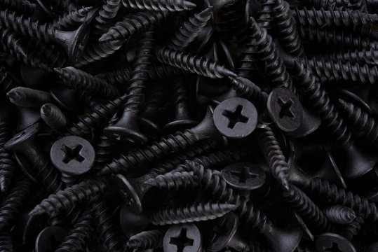 Full frame textured background  - pile of new metal black screws in close-up