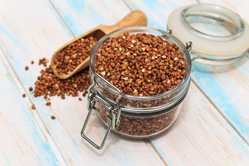 Buckwheat groats in a glass jar on a white wooden background. The concept of healthy nutrition and diet.