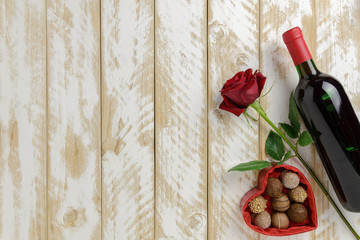 Valentines day romantic decoration with roses, wine and chocolate on a white wooden table. Top view, copy space.