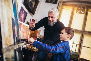 Father and son working and painting together in art studio