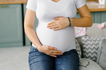 A woman holds her hands on her pregnant belly a woman