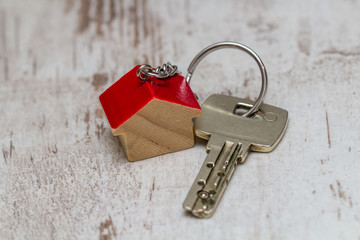 Schlüsselanhänger in Haus Form mit Schlüssel auf weißem Holz