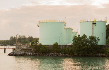 Industrial light green Fuel Tanks side  the sea at sunset time.