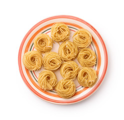Top view of plate with uncooked tagliolini pasta nests