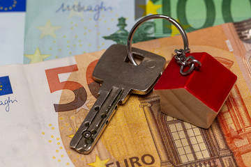 Schlüsselbund mit Häuschen Anhänger liegt auf Euro Geldscheinen