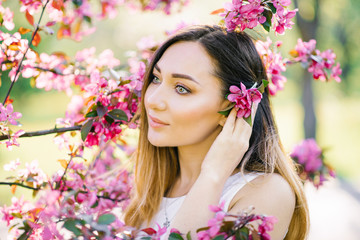 Beautiful girl with light big eyes in pink Apple blossoms in the spring