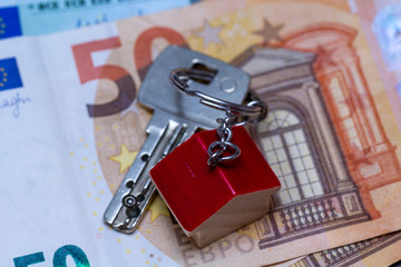 Schlüsselbund mit Schlüsselanhänger liegt auf Geldscheinen