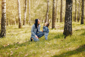 Naklejka na ściany i meble Beautiful mother with daughter. Family in a spring park. Woman in a blue jacket