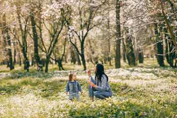 Beautiful mother with daughter. Family in a spring park. Woman in a blue jacket