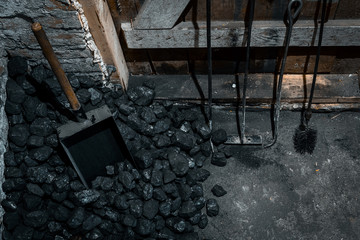 A coal shovel stuck in a pile of coalat the basement prepared for heating the house with.