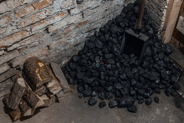Coal, wood and shovel on the floor at the basement prepared for heating the house with.
