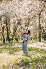 Beautiful mother with daughter. Family in a spring park. Woman in a blue jacket