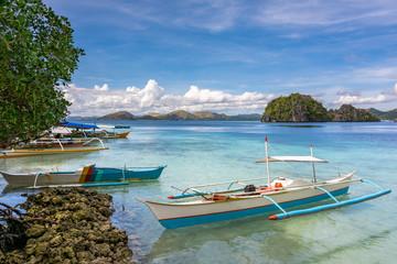 Traditional wooden Filipino boats by the beach of a small island in the sea, Coron Palawan...