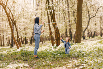 Fototapeta premium Beautiful mother with daughter. Family in a spring park. Woman in a blue jacket