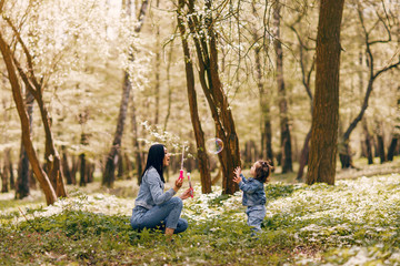 Beautiful mother with daughter. Family in a spring park. Woman in a blue jacket