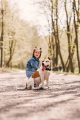 Beautiful little girl in a blue jacket. Child in a summer park with a dog