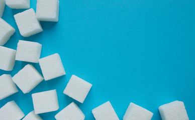 Square pieces of white sugar on a blue background close up in perspective
