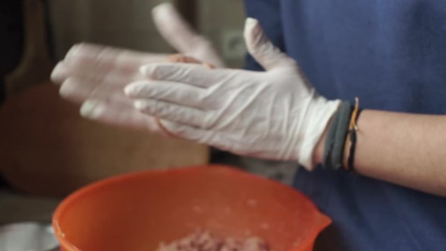 Footage of woman wearing white latex glove, knead sinced beef, making burgers