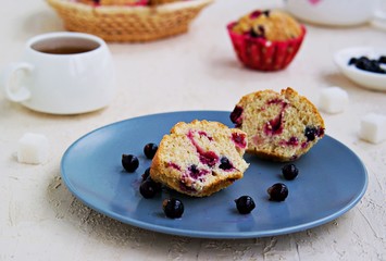 Sliced muffin with black currants on a blue plate on a light concrete background. American cuisine. Copyspace. Selective focus