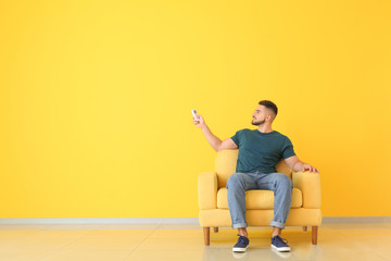 Young man switching on air conditioner at home