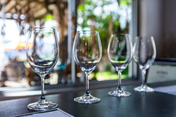 Side by side various sizes of wine empty glasses on a restaurant table selective focus view, goblets for drink and taste wines, tasting room stemware - obrazy, fototapety, plakaty