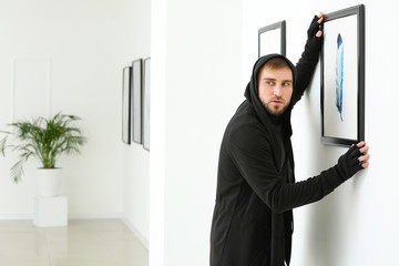 Thief stealing picture from art gallery