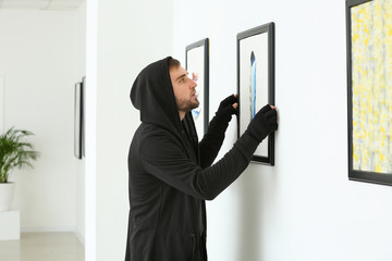 Thief stealing picture from art gallery