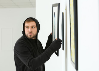 Thief stealing picture from art gallery