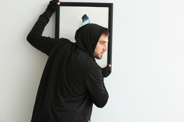 Thief stealing picture from art gallery