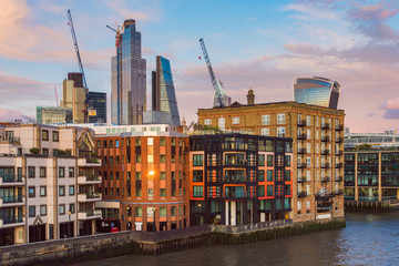 Fototapeta premium Apartment Buildings in Front of the Thames River and Modern Buildings of the City of London at Sunset