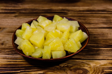 Ceramic plate with chopped canned pineapple on wooden table