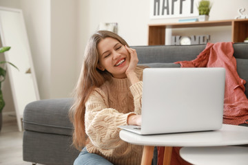 Happy woman with laptop resting at home