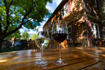 pair of white and red wine glasses on a wooden table close up selective focus, against old Canadian winery vineyard farmhouse cellar and tasting room