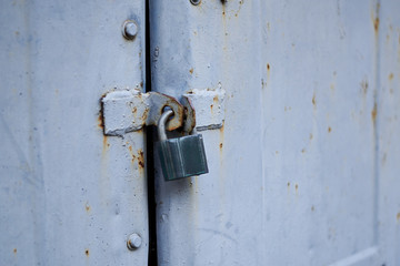 Old metal doors are closed on a padlock.