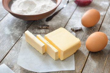 Fresh butter with products on wooden table