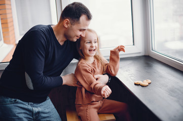 Family in a room. Little girl with a cookies. Father with daughter